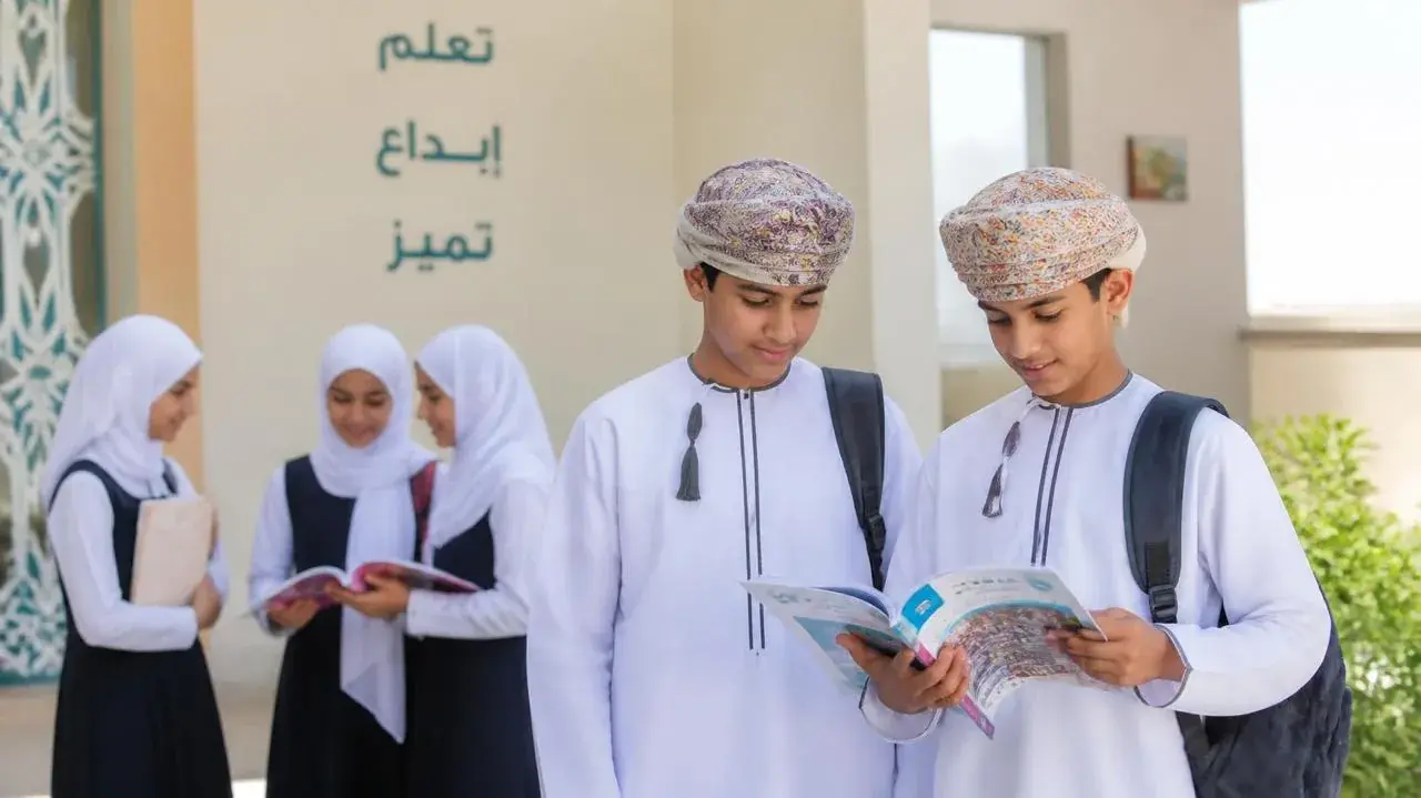 طلبة وطالبات في فناء المدرسة يتصفحون كتيّب «مهنتي»